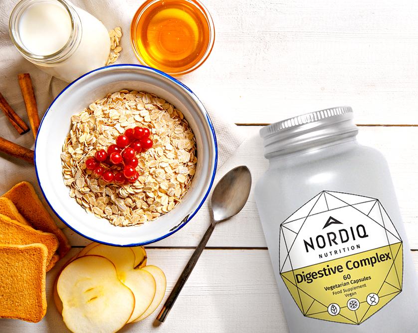 NORDIQ Nutrition Digestive Complex bottle and bowl of oatmeal with spoon and apples.